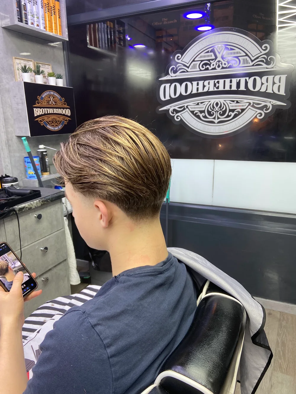 A finished haircut in front of the Brotherhood window logo