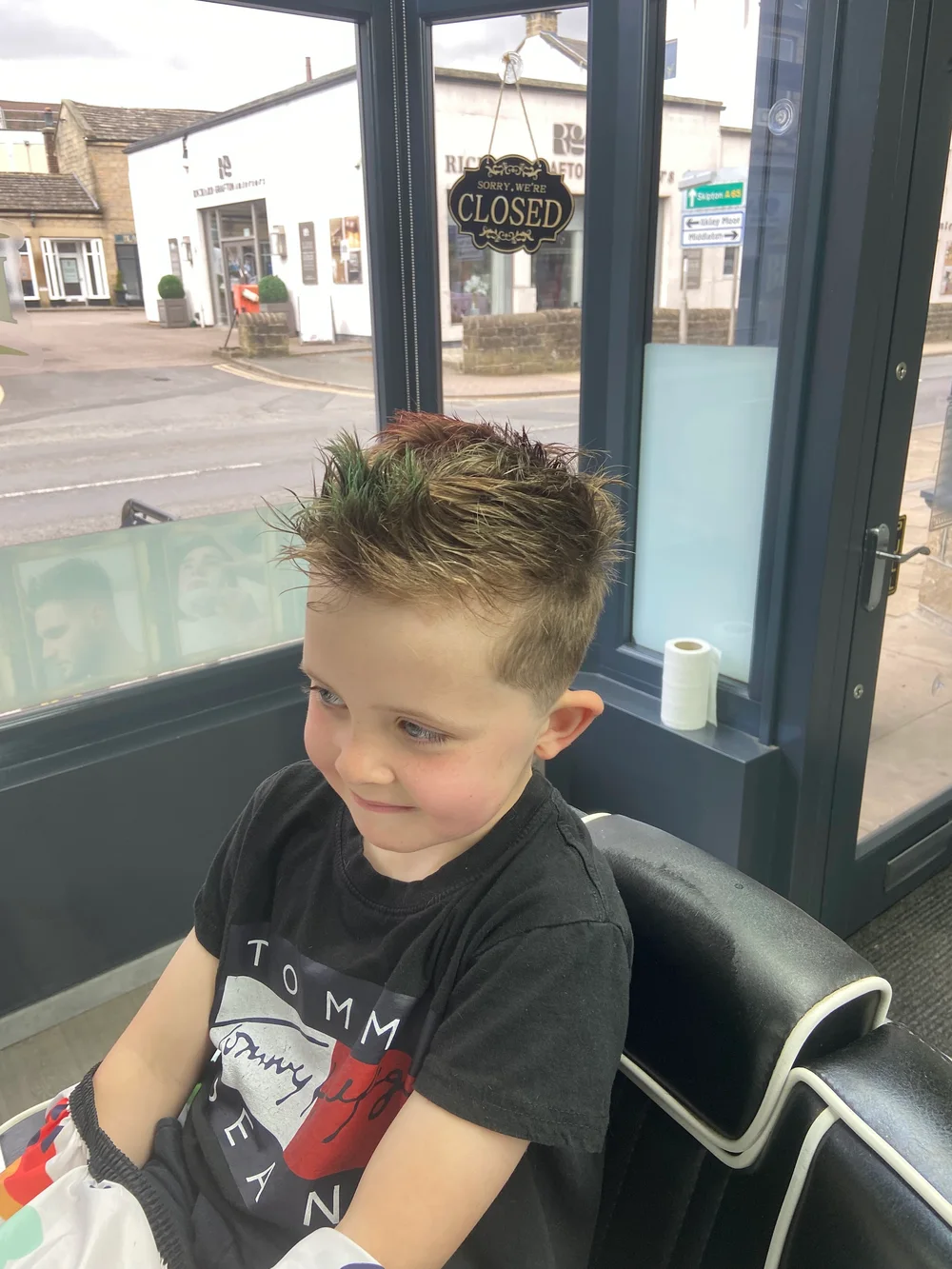 A child's finished haircut beside the shop window
